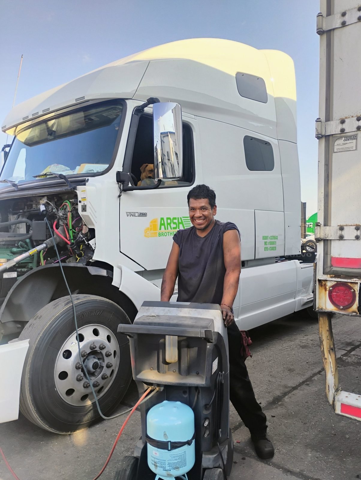 Smiling Bawa’s mechanic servicing a Volvo semi truck in Dallas, TX