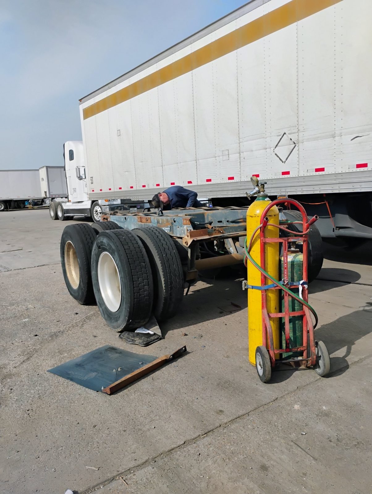 Mechanic welding a trailer frame with oxygen and acetylene cylinders in Dallas