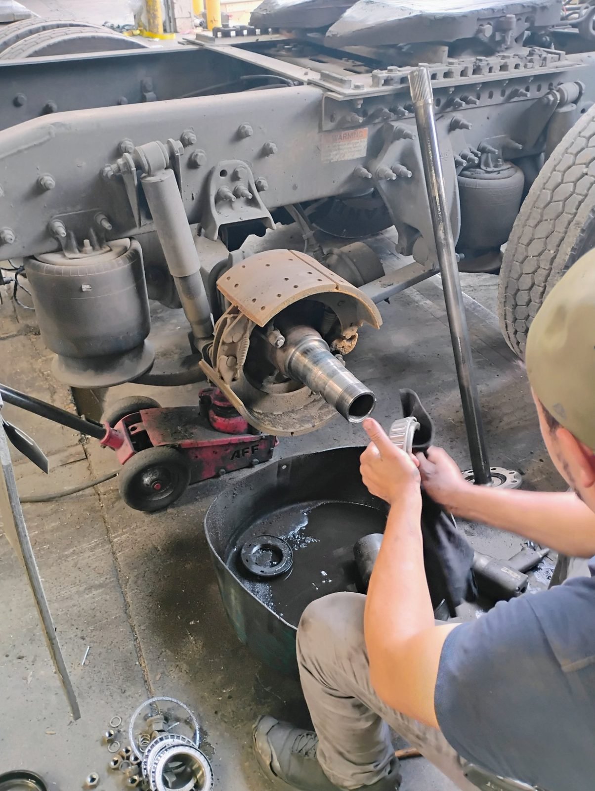 Technician working on a truck axle hub, brake shoe and wheel bearing in Dallas