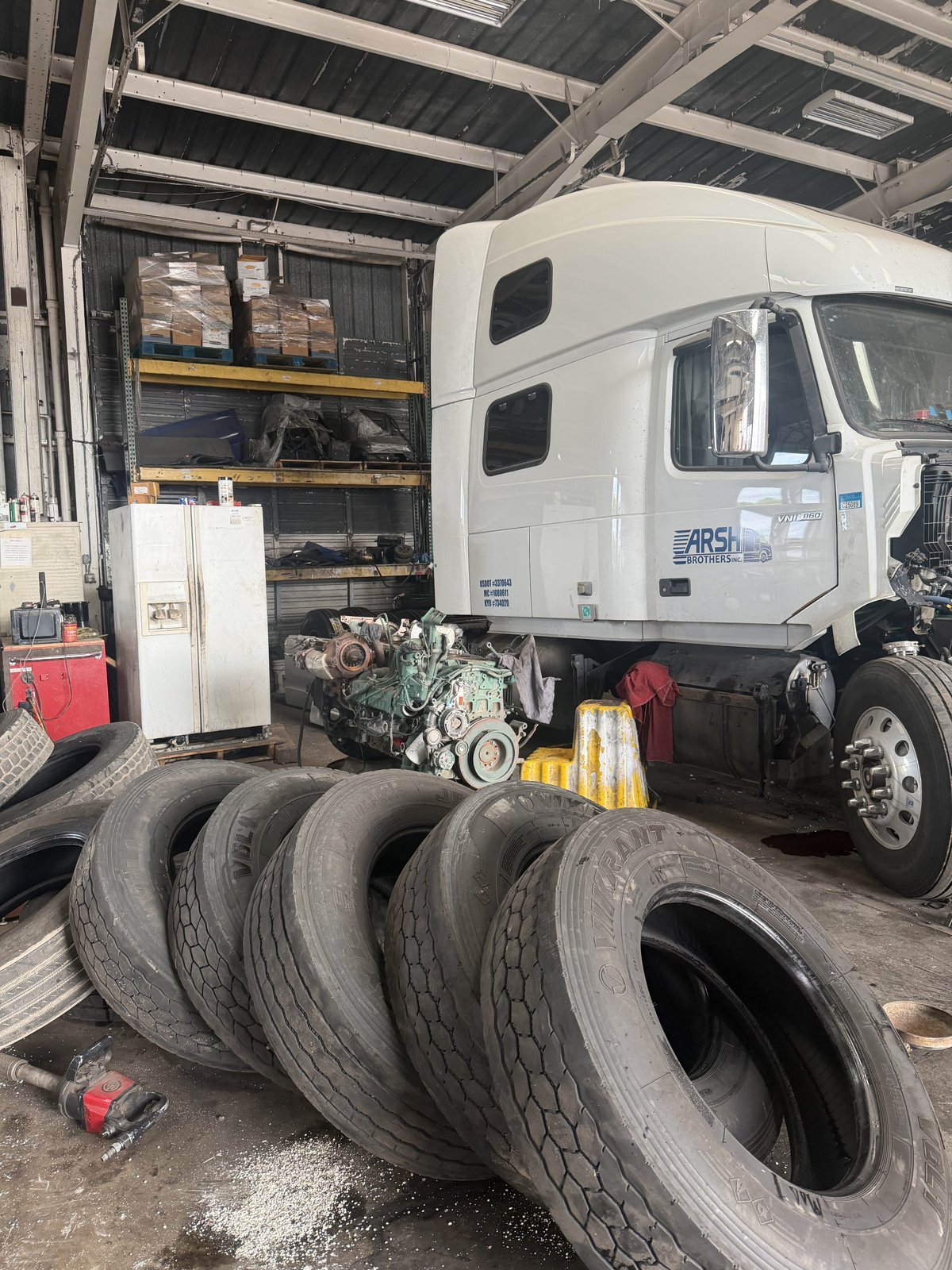 Stack of used truck tires next to a white semi truck in the Bawa’s shop bay in Dallas